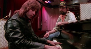 Movie still from “This Is Spinal Tap” (1984), directed by Rob Reiner – A man sitting next to another man playing a piano; Close Up shot, High angle