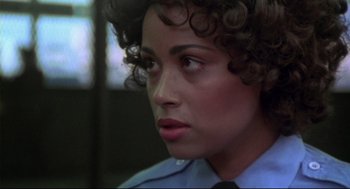 Movie still from “This Is Spinal Tap” (1984), directed by Rob Reiner – A woman in a police uniform looking to her left; Close Up shot, Over the shoulder angle