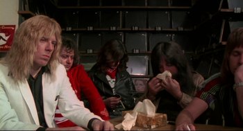 Movie still from “This Is Spinal Tap” (1984), directed by Rob Reiner – A group of people sitting at a table; Medium shot, Low angle
