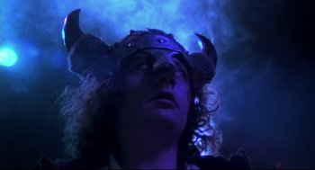 Movie still from “This Is Spinal Tap” (1984), directed by Rob Reiner – A person wearing a horned helmet with horns on their head; Close Up shot, Low angle