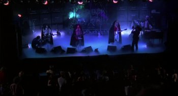 Movie still from “This Is Spinal Tap” (1984), directed by Rob Reiner – A group of people on a stage playing guitars; Wide shot, High angle