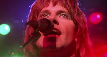 Movie still from “This Is Spinal Tap” (1984), directed by Rob Reiner – A person with red hair is singing into a microphone; Extreme Close Up shot, Low angle
