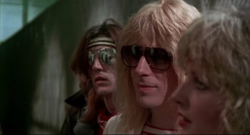 Movie still from “This Is Spinal Tap” (1984), directed by Rob Reiner – Three people wearing sunglasses; Close Up shot, Over the shoulder angle