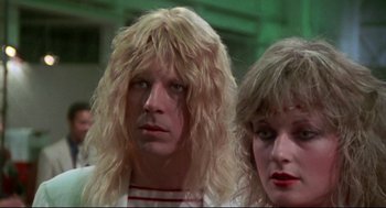 Movie still from “This Is Spinal Tap” (1984), directed by Rob Reiner – A man and a woman with long blonde hair; Close Up shot, Low angle