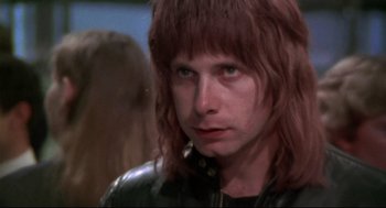 Movie still from “This Is Spinal Tap” (1984), directed by Rob Reiner – A man with long red hair wearing a leather jacket; Close Up shot, Low angle