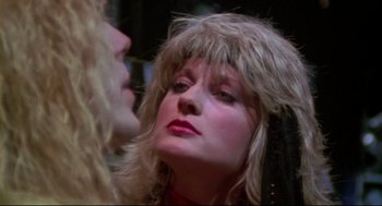 Movie still from “This Is Spinal Tap” (1984), directed by Rob Reiner – A woman with long blonde hair looking into a mirror; Close Up shot, Over the shoulder angle