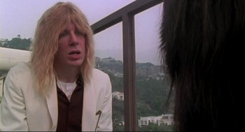 Movie still from “This Is Spinal Tap” (1984), directed by Rob Reiner – A man in a white jacket is talking to another man in a white jacket; Close Up shot, Over the shoulder angle