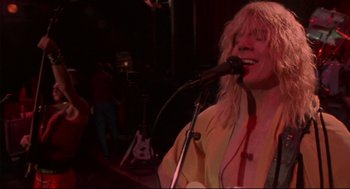 Movie still from “This Is Spinal Tap” (1984), directed by Rob Reiner – A woman singing into a microphone at a rock concert; Medium shot, Low angle