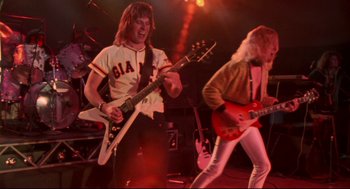 Movie still from “This Is Spinal Tap” (1984), directed by Rob Reiner – A couple of people that are playing a guitar; Medium shot, Low angle