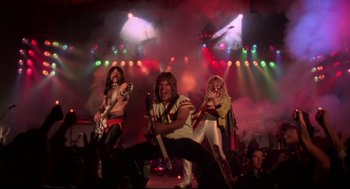 Movie still from “This Is Spinal Tap” (1984), directed by Rob Reiner – A group of people that are on a stage; Wide shot, Low angle