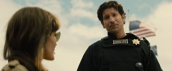 Movie still from “Those Who Wish Me Dead” (2021), directed by Taylor Sheridan – A man and a woman wearing black clothing and sunglasses; Close Up shot, Over the shoulder angle