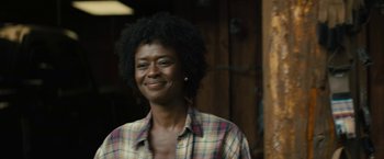 Movie still from “Those Who Wish Me Dead” (2021), directed by Taylor Sheridan – A woman smiling for the camera in front of a building; Close Up shot, Over the shoulder angle