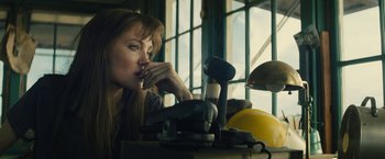 Movie still from “Those Who Wish Me Dead” (2021), directed by Taylor Sheridan – A woman sitting in front of a table with tools on top of it; Close Up shot, Low angle