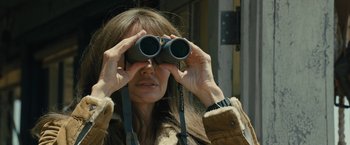 Movie still from “Those Who Wish Me Dead” (2021), directed by Taylor Sheridan – A woman looking through a pair of binoculars; Close Up shot, Over the shoulder angle