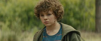 Movie still from “Those Who Wish Me Dead” (2021), directed by Taylor Sheridan – A young boy with brown curly hair and blue eyes; Close Up shot, High angle