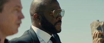 Movie still from “Those Who Wish Me Dead” (2021), directed by Taylor Sheridan – A person wearing a suit and sunglasses; Close Up shot, Low angle