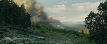 Movie still from “Those Who Wish Me Dead” (2021), directed by Taylor Sheridan – Smoke billows from a fire on the side of a mountain; Extreme Wide shot, High angle