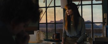 Movie still from “Those Who Wish Me Dead” (2021), directed by Taylor Sheridan – A woman standing in front of a window looking out at the mountains; Medium shot, Over the shoulder angle