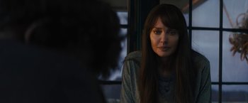 Movie still from “Those Who Wish Me Dead” (2021), directed by Taylor Sheridan – A woman sitting in front of a window looking at the camera; Close Up shot, Over the shoulder angle