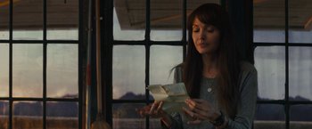 Movie still from “Those Who Wish Me Dead” (2021), directed by Taylor Sheridan – A woman holding an open envelope in front of a window; Medium shot, Over the shoulder angle
