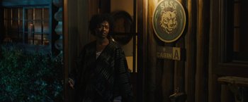 Movie still from “Those Who Wish Me Dead” (2021), directed by Taylor Sheridan – A person standing next to a sign in front of a building; Medium shot, Over the shoulder angle