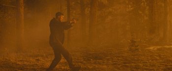 Movie still from “Those Who Wish Me Dead” (2021), directed by Taylor Sheridan – A man is holding a gun in the middle of a forest; Wide shot, Low angle