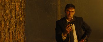 Movie still from “Those Who Wish Me Dead” (2021), directed by Taylor Sheridan – A man in a suit holding a gun in his hand; Medium shot, Low angle