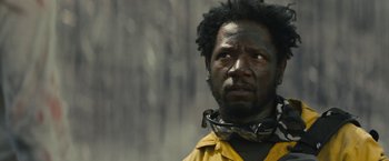 Movie still from “Those Who Wish Me Dead” (2021), directed by Taylor Sheridan – A man wearing a yellow jacket and a black neck brace; Close Up shot, Low angle