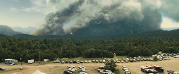 Movie still from “Those Who Wish Me Dead” (2021), directed by Taylor Sheridan – Cars parked in a parking lot in front of a forest fire; Extreme Wide shot, High angle