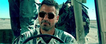 Movie still from “Three Kings” (1999), directed by David O. Russell – A person wearing sunglasses in a vehicle; Close Up shot, Over the shoulder angle