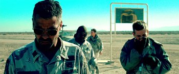 Movie still from “Three Kings” (1999), directed by David O. Russell – A group of men standing next to each other on a dirt field; Close Up shot, Over the shoulder angle