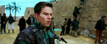 Movie still from “Three Kings” (1999), directed by David O. Russell – A man holding a gun while standing next to a wall; Close Up shot, Over the shoulder angle