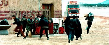 Movie still from “Three Kings” (1999), directed by David O. Russell – A group of people walking down a street; Wide shot, Over the shoulder angle