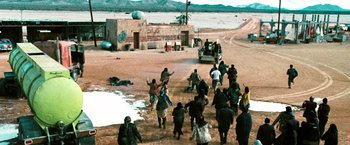 Movie still from “Three Kings” (1999), directed by David O. Russell – A group of people walking across a dirt road; Extreme Wide shot, High angle