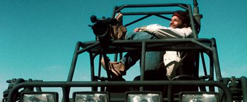 Movie still from “Three Kings” (1999), directed by David O. Russell – A man sitting in the back of an off - road vehicle; Close Up shot, Low angle