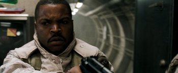 Movie still from “Three Kings” (1999), directed by David O. Russell – A man holding a gun while standing next to a wall; Close Up shot, Low angle