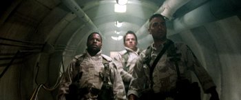 Movie still from “Three Kings” (1999), directed by David O. Russell – A group of men standing next to each other in a tunnel; Medium shot, Low angle