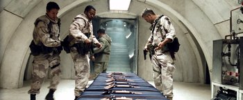 Movie still from “Three Kings” (1999), directed by David O. Russell – A group of men standing next to each other in a room; Medium shot, Low angle