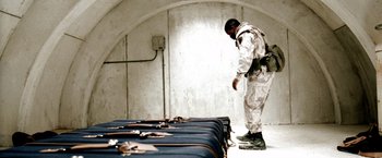 Movie still from “Three Kings” (1999), directed by David O. Russell – A man standing next to a row of suitcases; Wide shot, High angle