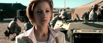 Movie still from “Three Kings” (1999), directed by David O. Russell – A woman standing in front of a man in a helmet; Close Up shot, Low angle