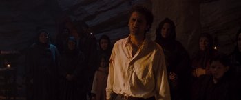 Movie still from “Three Kings” (1999), directed by David O. Russell – A group of people standing around a man in the dark; Medium shot, Over the shoulder angle