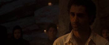 Movie still from “Three Kings” (1999), directed by David O. Russell – A man standing next to another man in a dark room; Close Up shot, Over the shoulder angle
