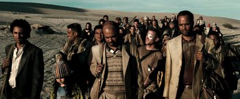 Movie still from “Three Kings” (1999), directed by David O. Russell – A group of people standing in the desert; Wide shot, Over the shoulder angle