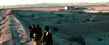 Movie still from “Three Kings” (1999), directed by David O. Russell – A group of people walking across a dirt field; Extreme Wide shot, High angle
