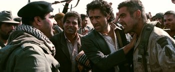 Movie still from “Three Kings” (1999), directed by David O. Russell – A group of men standing next to each other on a street; Medium shot, Over the shoulder angle