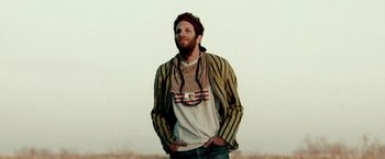 Movie still from “Three Kings” (1999), directed by David O. Russell – A man standing in a field with his hands in his pockets; Close Up shot, Low angle