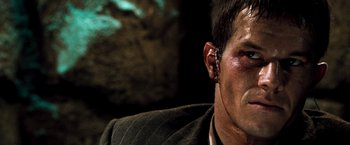 Movie still from “Three Kings” (1999), directed by David O. Russell – A person wearing a suit and ear piece; Close Up shot, Over the shoulder angle