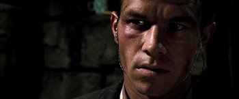 Movie still from “Three Kings” (1999), directed by David O. Russell – A person wearing a jacket and ear buds; Close Up shot, Over the shoulder angle