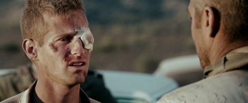 Movie still from “Three Kings” (1999), directed by David O. Russell – A person with a bandage on his eye; Close Up shot, Over the shoulder angle