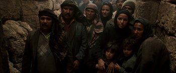 Movie still from “Three Kings” (1999), directed by David O. Russell – A group of people standing around each other in a room; Medium shot, High angle